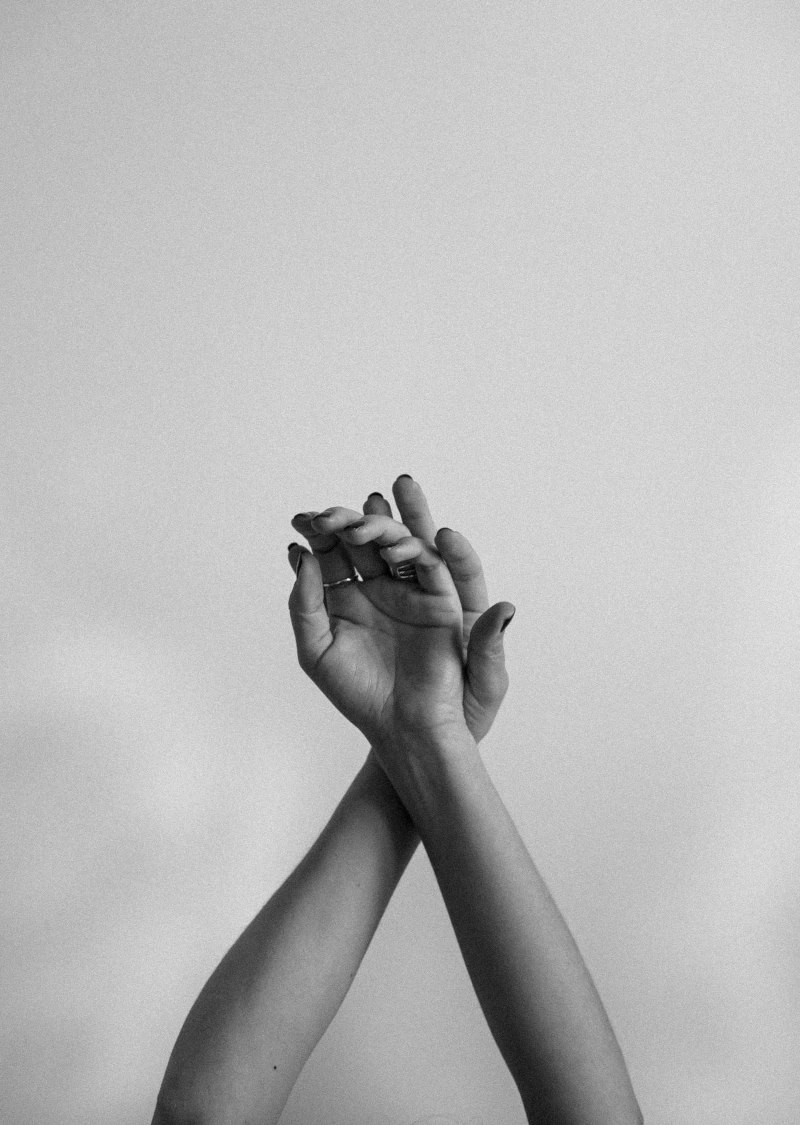 Deux mains entrelacées, levées vers le ciel, symbolisant la connexion, l'harmonie et la relation humaine dans une esthétique minimaliste en noir et blanc.